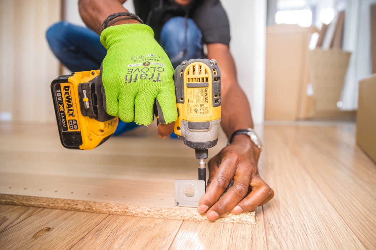 why-choose-us-01 Man using a power drill for home improvement on a wooden floor with precision.